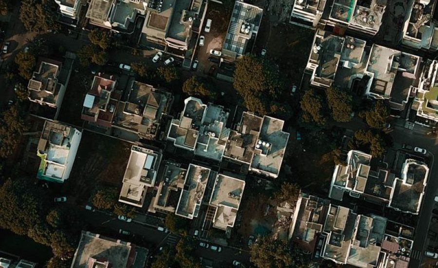 High-angle aerial view capturing residential buildings surrounded by greenery in an urban area during the day.